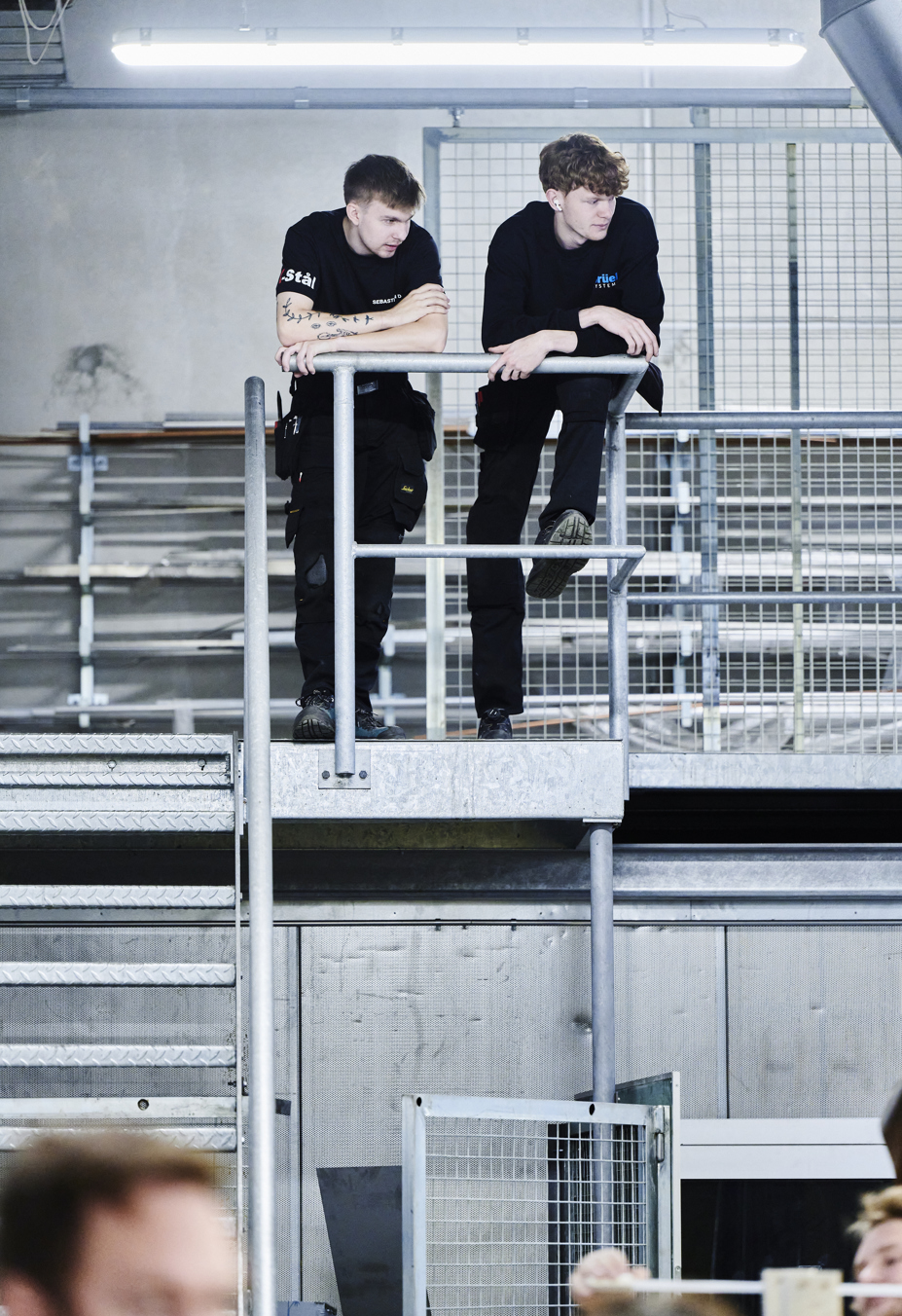 Smede-drenge stå oppe på trappe og kigger ud over værkstedet