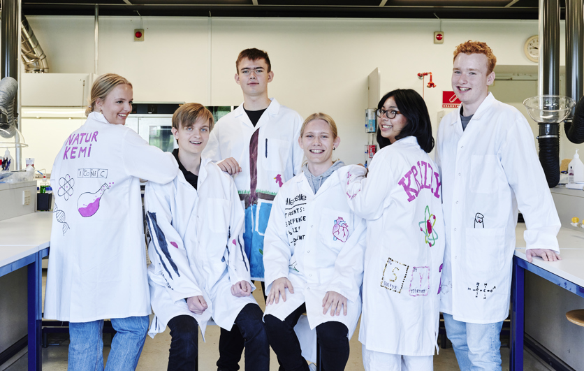 Naturens kemi, elever står i kitler i laboratorie