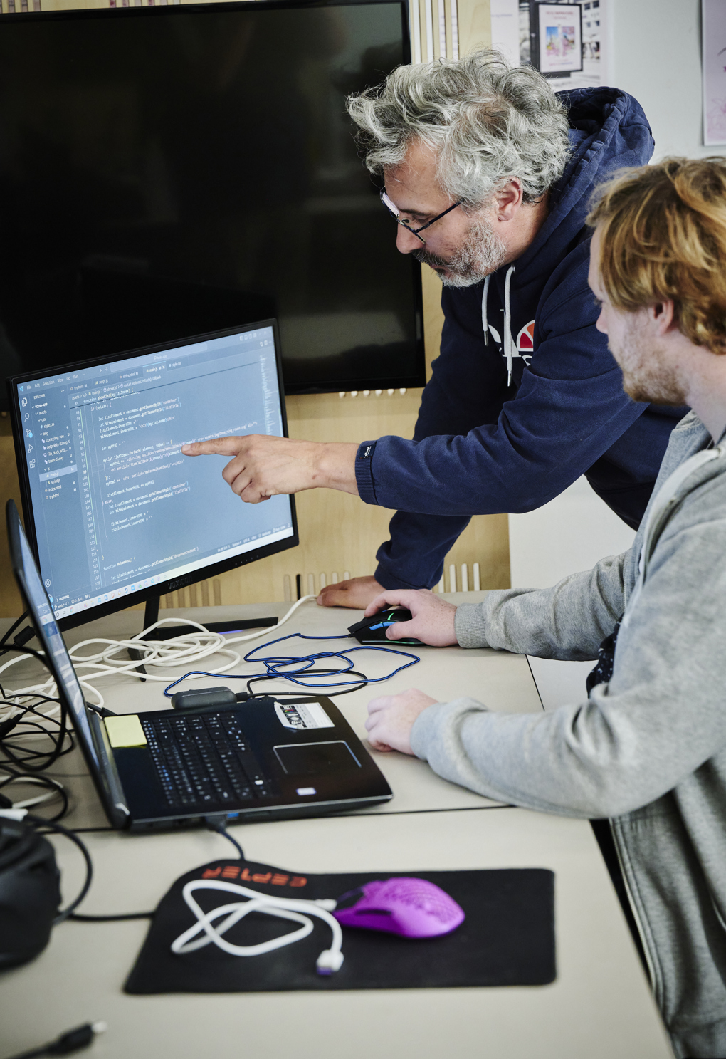 Webudvikler, underviser og elev kigger på skærm
