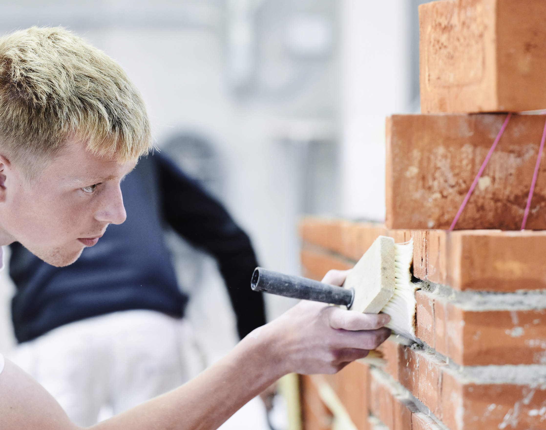 Dreng fejer sin væg med murerkost