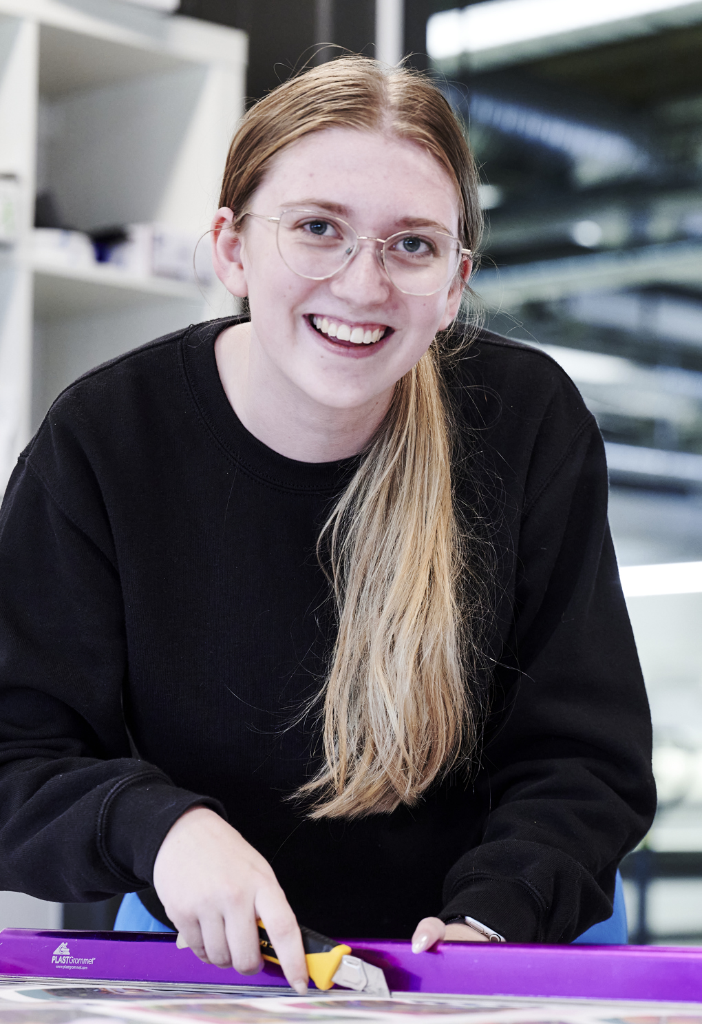 Grafisk tekniker-elev skærer ved skærebord