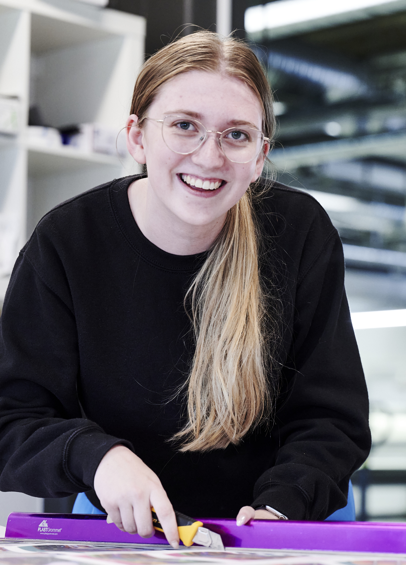 Grafisk tekniker-elev skærer ved skærebord