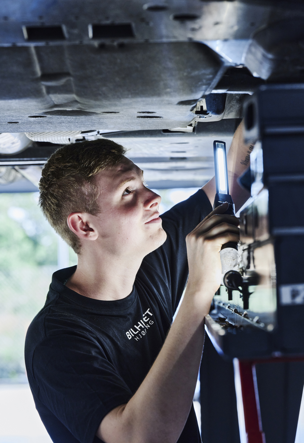 Personvognsmekaniker-elev under bil