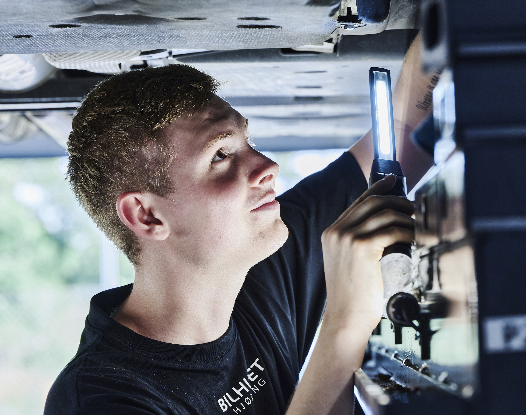 Personvognsmekaniker-elev under bil