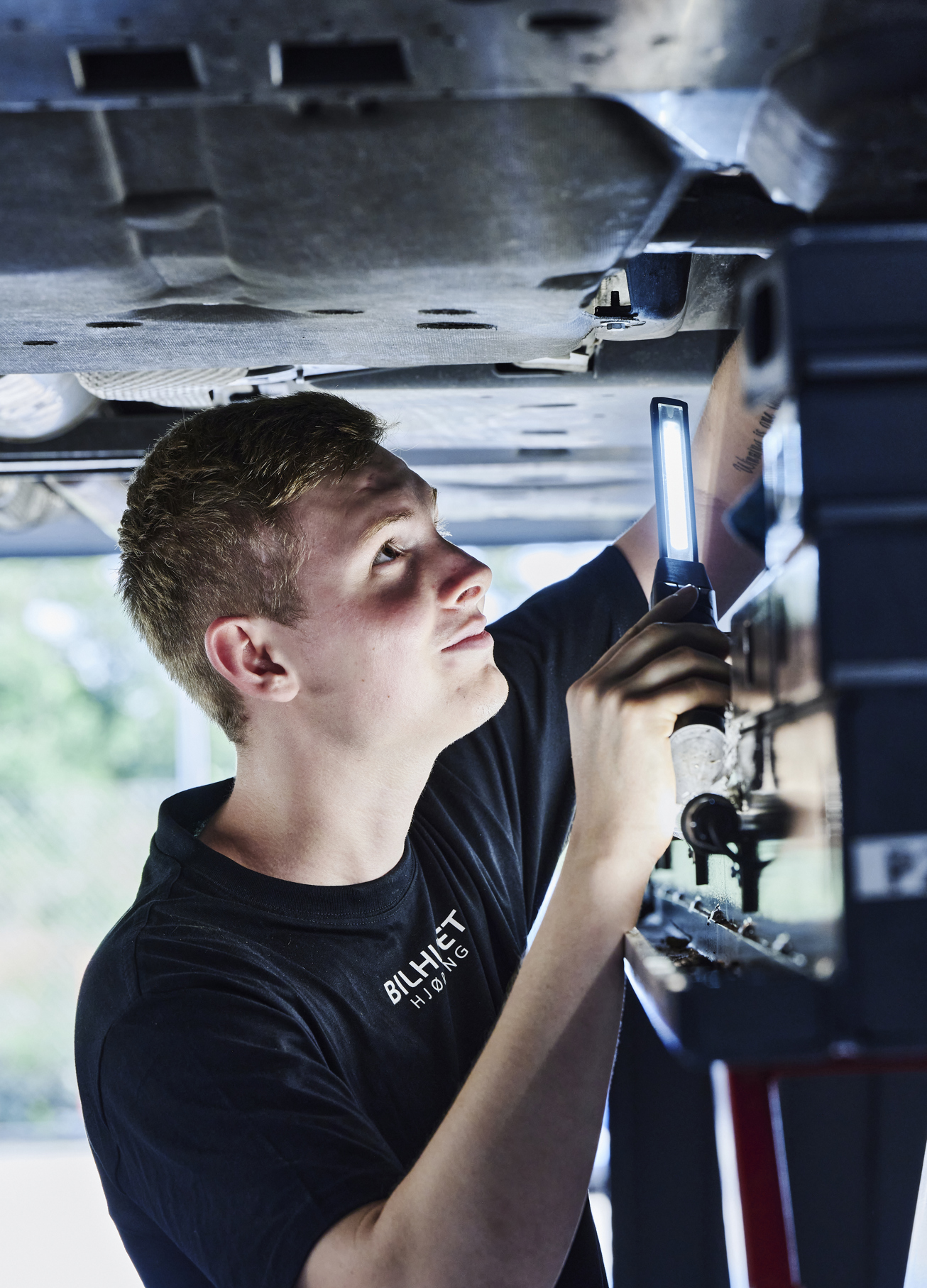 Personvognsmekaniker-elev under bil